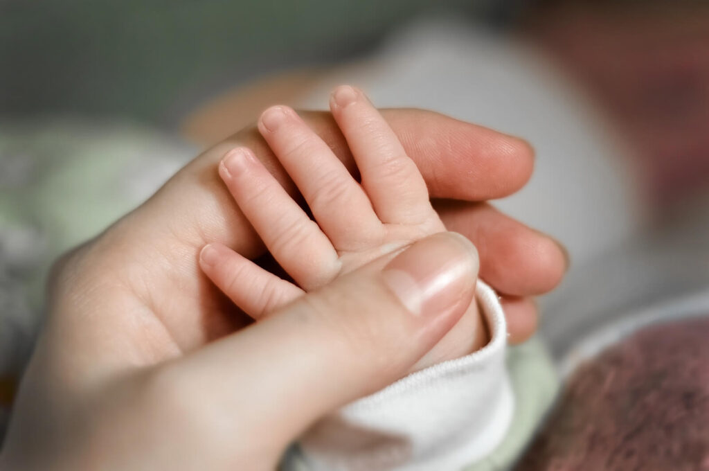 An infant hand being held by a mothers hand. We offer postpartum OCD in American Fork, UT to help all the mothers out there. Let us be your support through your ERP therapy journey.