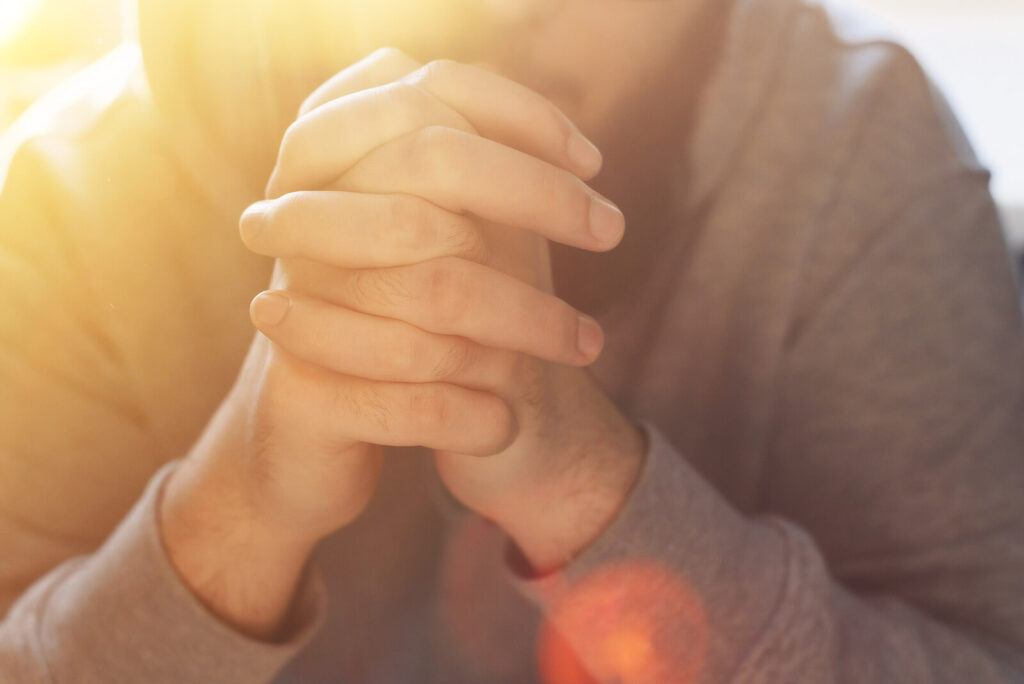 An individual folding their hands together. If you are having a hard time navigating family relationships after you transitioned from their faith, contact us today. Our faith transition therapists are ready to help.