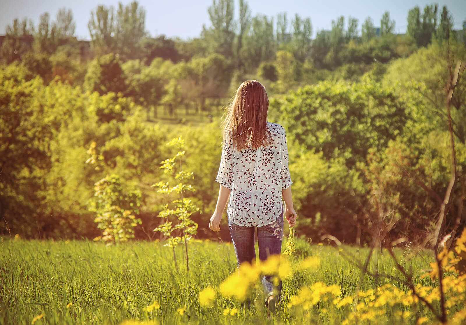 A woman walking away into a field. Talk to a faith transition therapist in American Fork, UT today to heal from religious trauma. Learn more here!