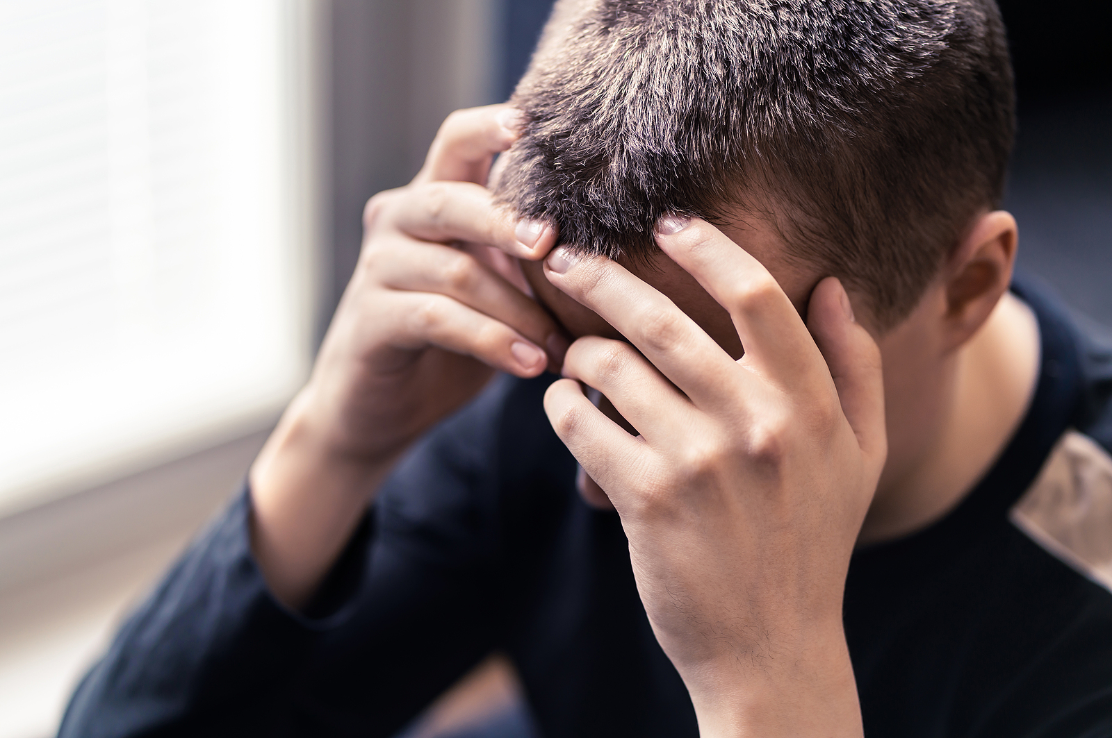 A close up of a teen covering their face. This could represent the stressors teens experience that therapy for teens in American Fork, UT can offer. Search for an anxiety therapist American Fork, UT to learn more about the support anxiety and depression therapists in American Fork offer.