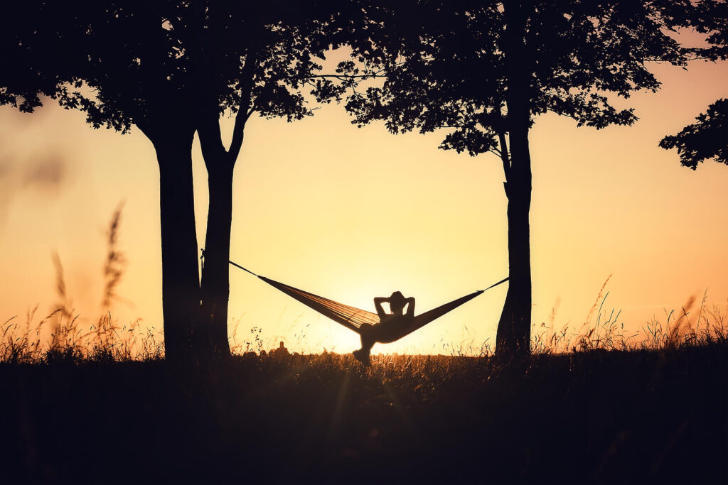 A person sits in a hammock with arms behind their head. This could represent learning to relax and promote self care with anxiety treatment in American Fork, UT. Search for anxiety counseling American Fork, UT and how therapists American Fork UT can help. 
