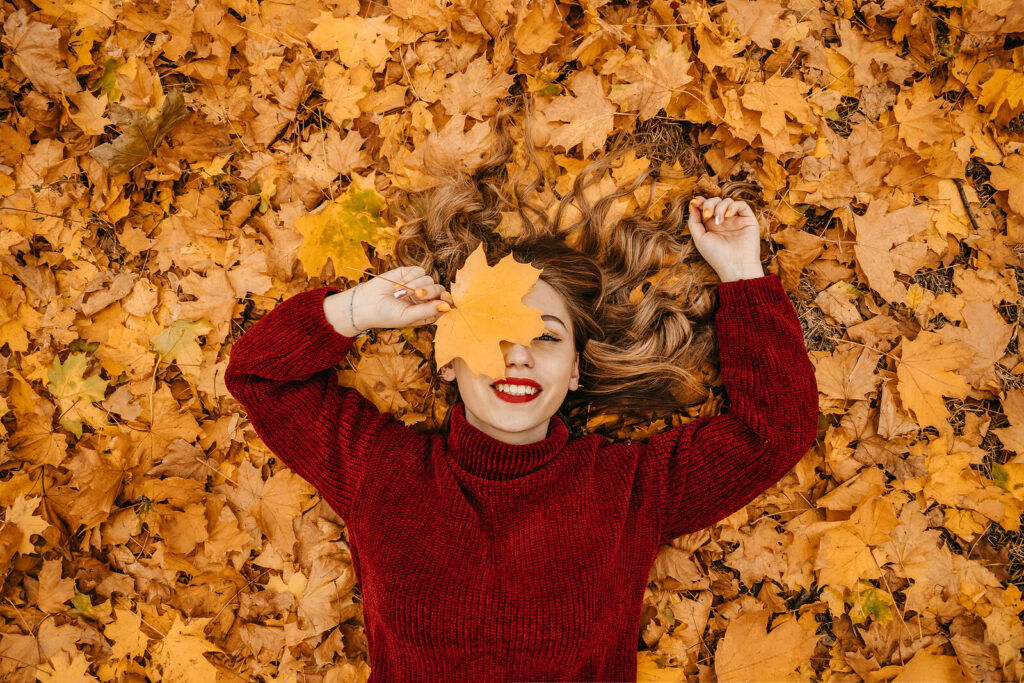 A woman holds a leaf in front of her face while smiling. Learn how therapy for depression in American Fork, UT can offer support with overcoming SAD. Search for therapy for teenage depression near me and how depression therapists in American Fork, UT can help. 
