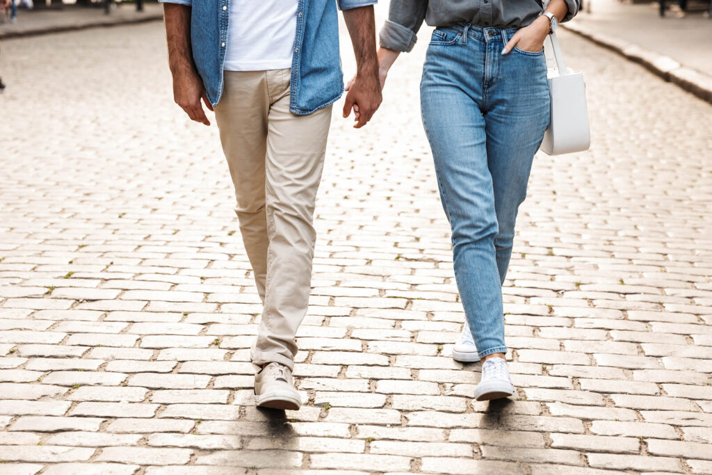 A couple hold hands while walking down a brick road. This could represent the trust that is rebuilt after betrayal trauma therapy in American Fork, UT. Learn more about couples therapy in American Fork, UT by searching for attachment trauma in American Fork, UT or contacting a therapist for couples today.