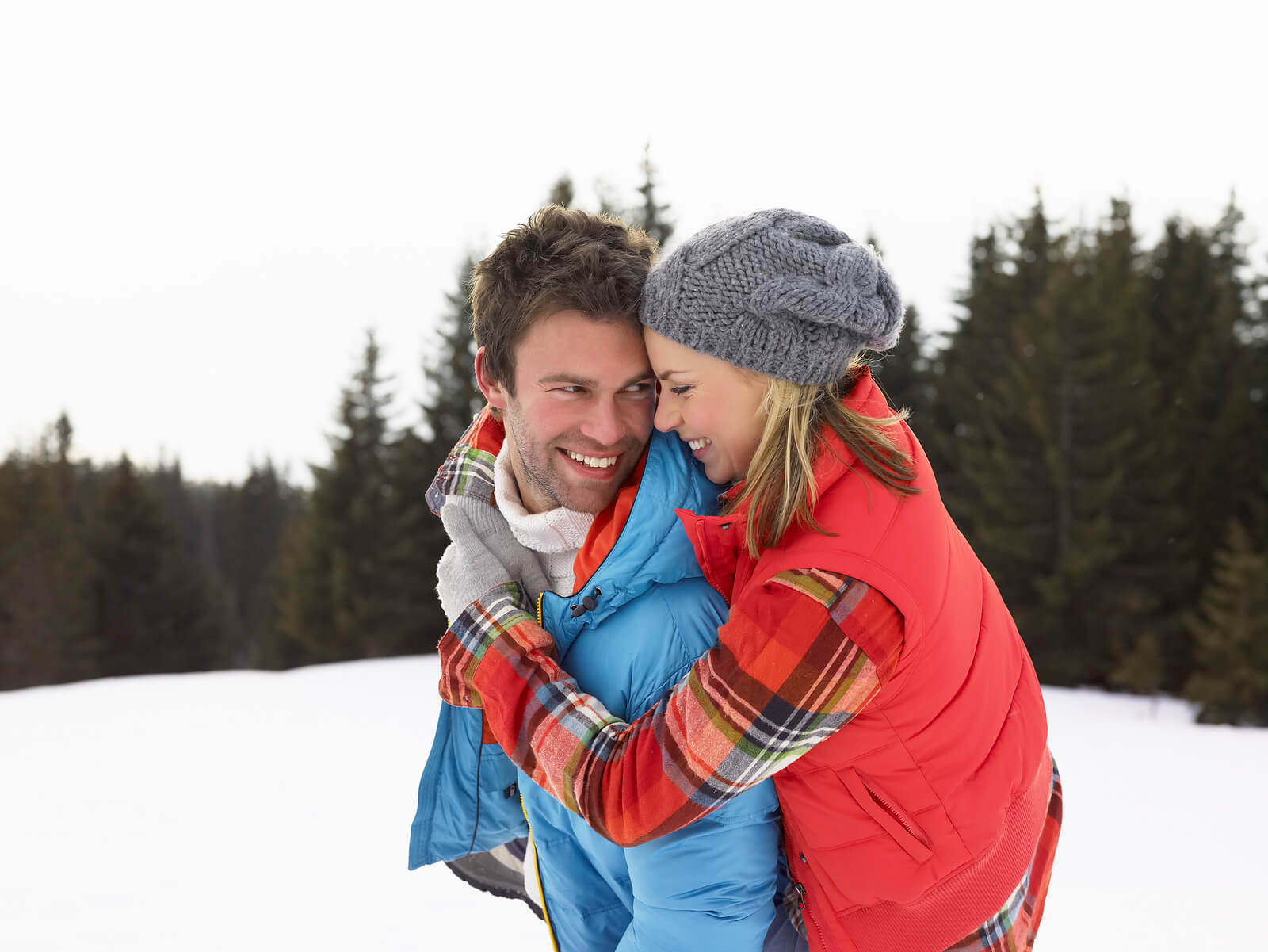 A couple wearing winter jackets smile while standing in the snow and embracing. This could represent the bonds cultivated from marriage counseling American Fork, UT. Search for couples therapy in American Fork, UT today to learn more.