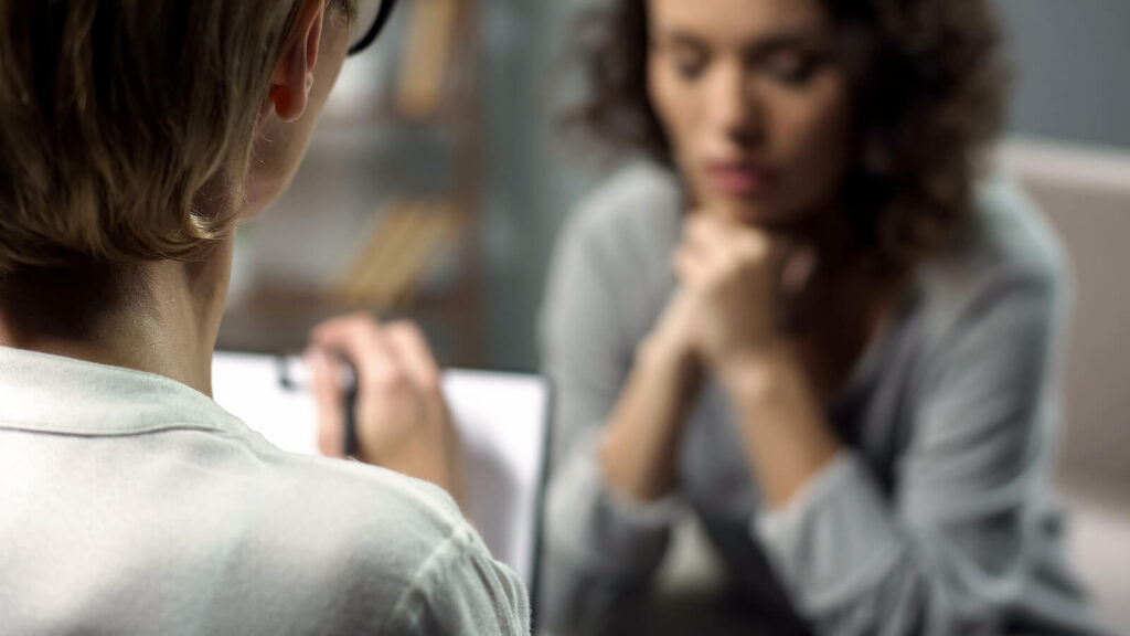 A close up of a woman taking notes while sitting across from a woman. This could represent the support a therapist in American Fork can offer contact a family therapist American Fork, UT for support with helping loved ones through a mental health crisis.