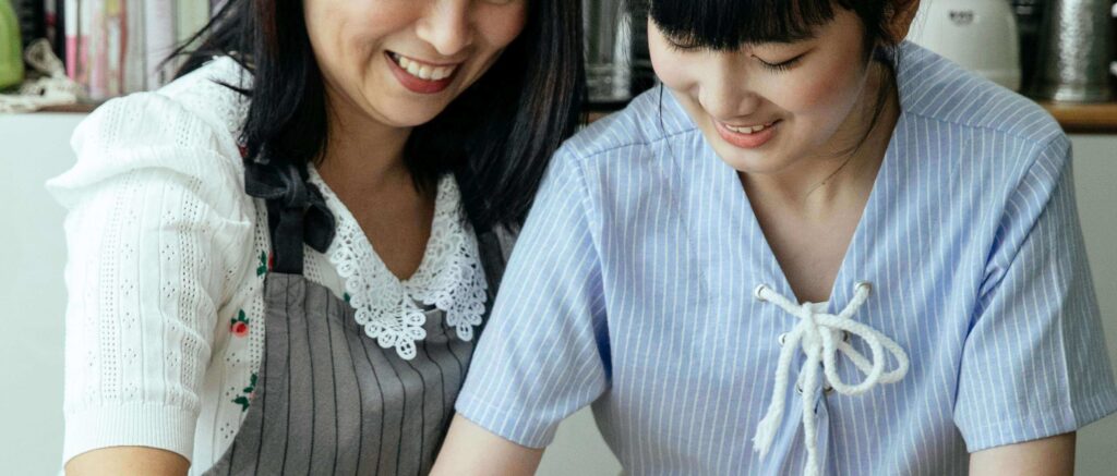 A mother and her teenage daughter smile together while preparing food in a cozy kitchen. Learn more about the support therapy for teens in American Fork, UT can offer. Search for therapist for teens American Fork, UT and how a family therapist American Fork, UT today. 
