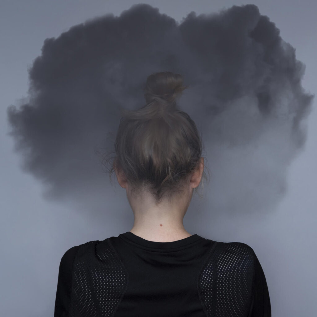 A woman, seen from behind, has a dark, smoky cloud hovering over her head. The image visually represents feelings of depression, anxiety, or past trauma that a trauma therapist in American Fork, UT can address. Learn more about attachment trauma in American Fork, UT and how betrayal trauma therapy in American Fork, UT can help.
